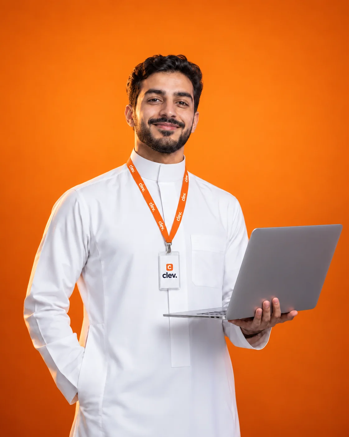 رائد أعمال سعودي يبتسم بثقة ويحمل حاسوبًا محمولًا